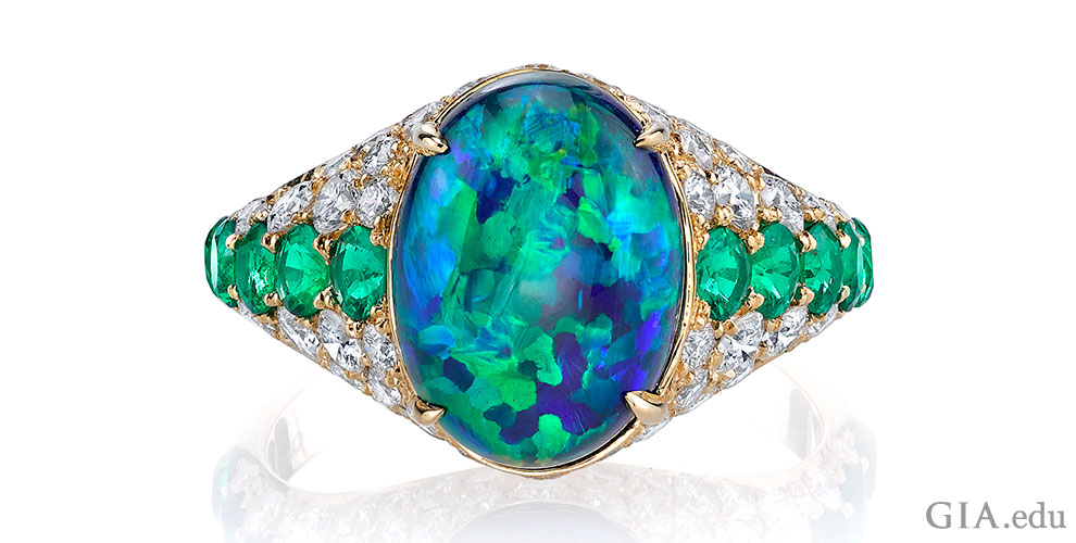 3.50 ct black opal, emerald and diamond ring. Set in 18k yellow gold.