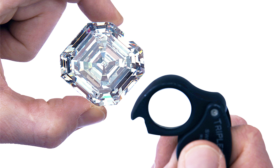 A jeweler examines a step cut, D, VVS1 diamond with a loupe.